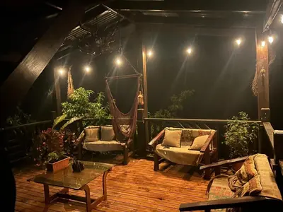 a patio with a hammock and chairs on a wooden deck at Cabaña de Montaña El Jardin in Jardín
