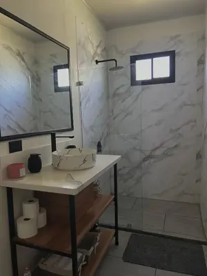 a bathroom with a shower with a sink and a mirror at Casa Los Cedros in Río Cuarto