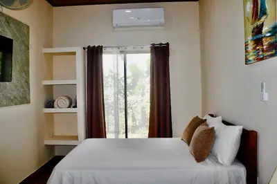 a bedroom with a white bed and a window at Rio Celeste Birds Garden Apartment with Air Conditioning Comfort and Privacy in a Natural Environment 4 in Upala