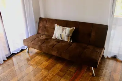 a brown couch with a pillow on it in a room at Rio Celeste Birds Garden Apartment with Air Conditioning Comfort and Privacy in a Natural Environment 4 in Upala