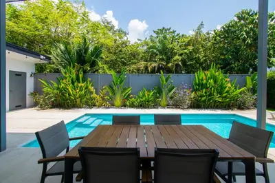 a patio with a wooden table and chairs next to a swimming pool at New! 3 Bedroom Villa in Uvita, Large Pool! in Uvita