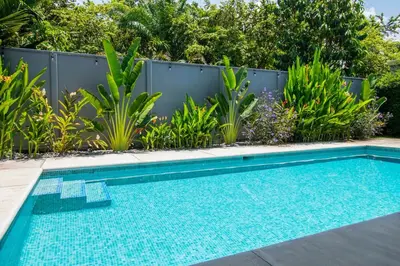 a swimming pool in front of a fence with plants at New! 3 Bedroom Villa in Uvita, Large Pool! in Uvita