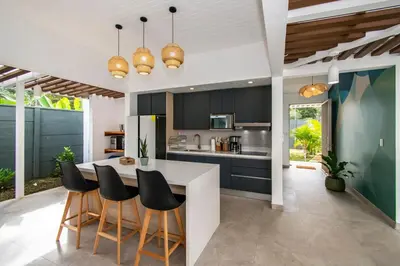 a kitchen with black cabinets and a table and chairs at NEW! Villa, 3bdrs with AC, Pool, close to Marino Ballena in Uvita