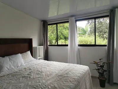 a bedroom with a bed and two windows at Casa Mi Bello Arenal, Rio el Salto and Fortuna in Fortuna