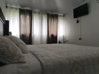 a bedroom with a bed with white sheets and windows at Casa Mi Bello Arenal, Rio el Salto and Fortuna in Fortuna