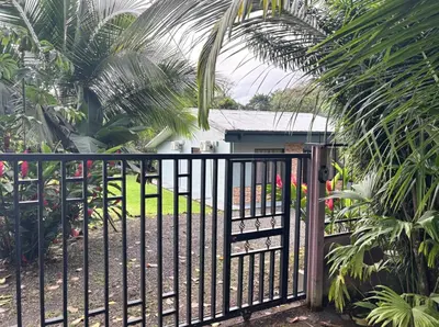 a gate in front of a house with palm trees at Casa Mi Bello Arenal, Rio el Salto and Fortuna in Fortuna