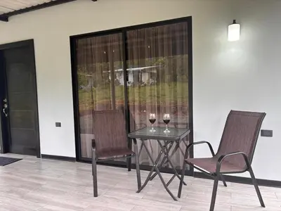 two glasses of wine sitting on a table with two chairs at Harmony Home La Fortuna in Fortuna