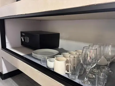 a shelf with glasses and plates and wine glasses at Harmony Home La Fortuna in Fortuna