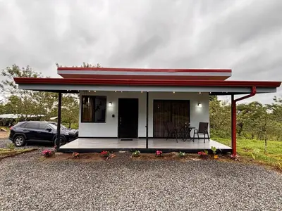 a small house with a red roof and a porch at Harmony Home La Fortuna in Fortuna