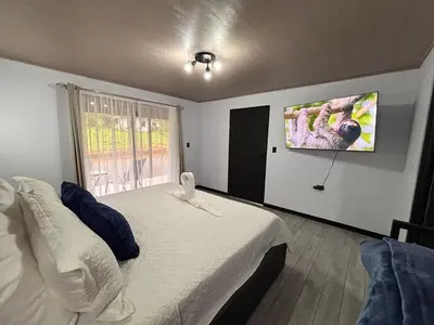 a bedroom with a bed and a tv on the wall at Harmony Home La Fortuna in Fortuna