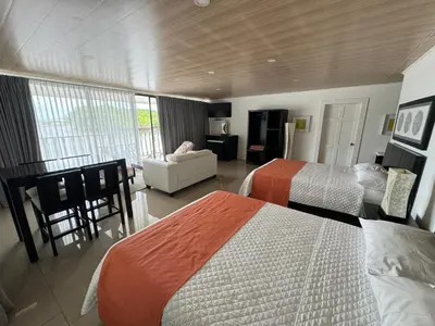 a hotel room with two beds and a living room at Hotel y Restaurante Costa del Sol in Mata de Limón