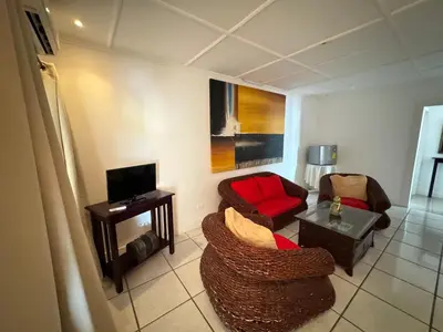 a living room with two chairs and a tv at Hotel y Restaurante Costa del Sol in Mata de Limón
