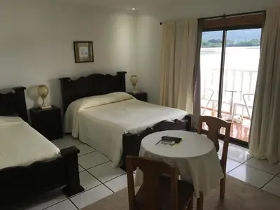 a bedroom with two beds and a table and a window at Hotel y Restaurante Costa del Sol in Mata de Limón