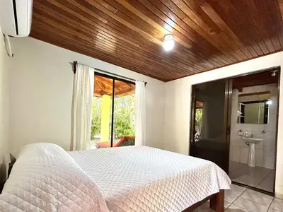 a bedroom with a white bed and a bathroom at Casa Fabis en Playa Junquillal, Playa a 600m in Santa Cruz