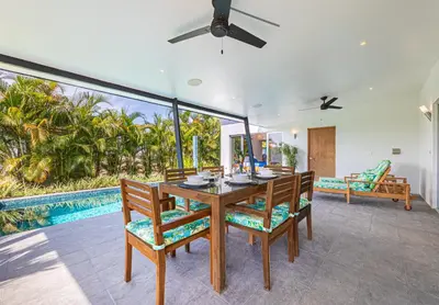 a dining room with a table and chairs and a pool at Villa Dos Vistas in Uvita
