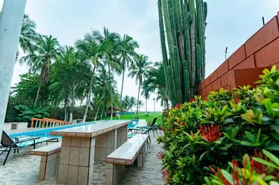 a resort with a pool and benches and palm trees at Casa Rector - Beach House Rental in El Roble