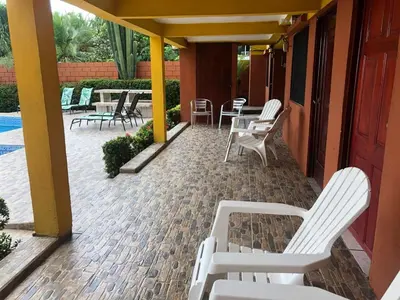 a patio with white chairs and tables and a pool at Casa Rector - Beach House Rental in El Roble