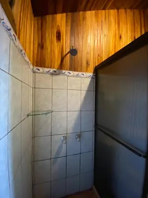 a bathroom with a shower and a tiled wall at Makena Rancho in Monteverde Costa Rica
