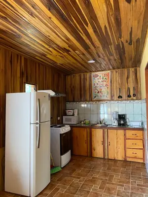 a kitchen with a white refrigerator and wooden walls at Makena Rancho in Monteverde Costa Rica