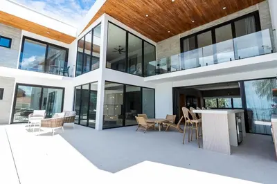 a large glass building with a table and chairs at CASA AZUL - Luxury Beachfront Mansion in Potrero