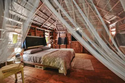 a bedroom with a bed in a wooden house at Flor y Bambu in Playa Grande
