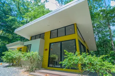 a yellow and white house with trees at Selva Color - Forest & Beach EcoLodge in Quebrada Ganado