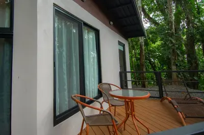 a porch with two chairs and a table on a balcony at Selva Color - Forest & Beach EcoLodge in Quebrada Ganado