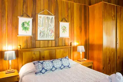 a bedroom with a bed with wooden walls and two lamps at Finca Luna Nueva Lodge in Fortuna
