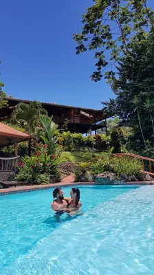 two people are sitting in a swimming pool at Finca Luna Nueva Lodge in Fortuna