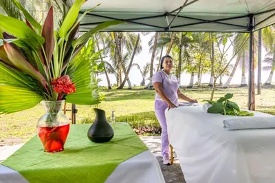 a woman standing under an umbrella next to two tables at Hotel Tortuguero Beachfront in Tortuguero