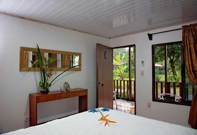 a bedroom with a bed and a view of a porch at Hotel Tortuguero Beachfront in Tortuguero