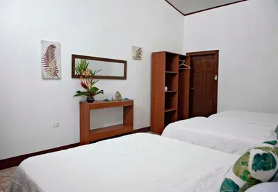 a bedroom with two beds and a mirror and a cabinet at Hotel Tortuguero Beachfront in Tortuguero