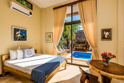 a bedroom with a bed and a table and a window at Villa Nautilus in Tamarindo