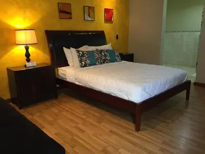 a bedroom with a bed and a lamp on a wooden floor at Hotel Vista De Golf, San Jose Aeropuerto, Costa Rica in San José