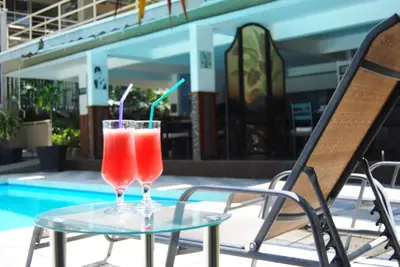two drinks on a glass table next to a pool at Hotel Vista De Golf, San Jose Aeropuerto, Costa Rica in San José