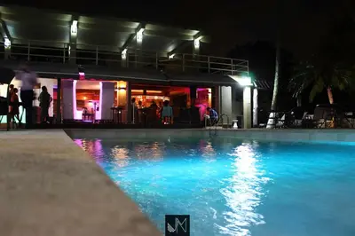 a swimming pool at night with people standing around at Hotel Vista De Golf, San Jose Aeropuerto, Costa Rica in San José