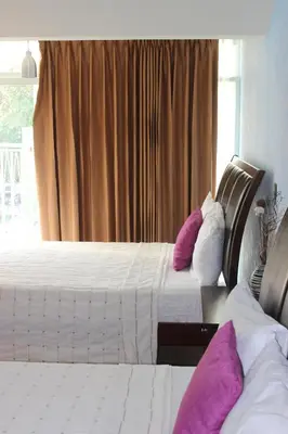 two beds in a hotel room with purple pillows at Hotel Vista De Golf, San Jose Aeropuerto, Costa Rica in San José