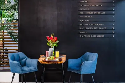 a table with two blue chairs and a vase of flowers at In the Shade Hotel - Coworking - 300Mbit - Adults Only in Tamarindo