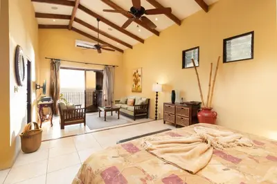 a bedroom with a bed and a living room at Stunning Villa with Oceanview, Private Pool, Soaking Tub & Picturesque Balcony in Playa Flamingo