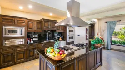 a kitchen with wooden cabinets and a bowl of fruit on a counter at Stunning Luxury Mansion in Playa Flamingo with Six Bedrooms and Beachfront Access in Playa Flamingo
