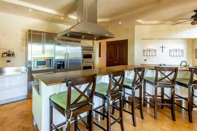 a kitchen with a large island with bar stools at Elegant Mediterranean-Style Mansion with Beachfront Views and Private Infinity Pool in Playa Flamingo