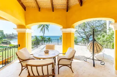 a patio with a table and chairs and the ocean at Elegant Mediterranean-Style Mansion with Beachfront Views and Private Infinity Pool in Playa Flamingo