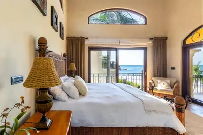 a bedroom with a large bed and a balcony at Elegant Mediterranean-Style Mansion with Beachfront Views and Private Infinity Pool in Playa Flamingo