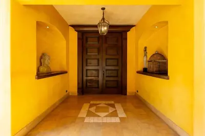 a hallway with yellow walls and a door with a bird cage at Elegant Mediterranean-Style Mansion with Beachfront Views and Private Infinity Pool in Playa Flamingo
