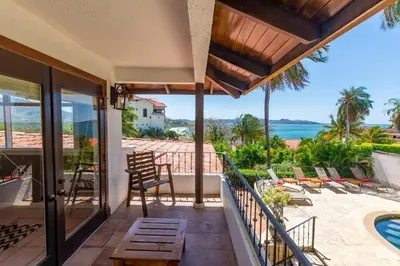 a house with a balcony with a view of the ocean at Luxury Five-Bedroom Oasis in Playa Flamingo with a Private Pool and Stylish Decor in Playa Flamingo