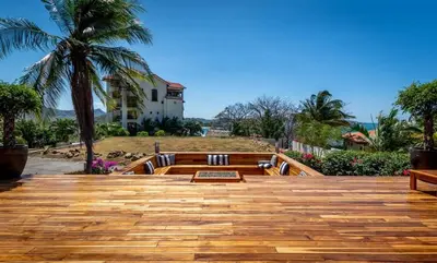 a wooden deck with a palm tree and a house at Luxury Five-Bedroom Oasis in Playa Flamingo with a Private Pool and Stylish Decor in Playa Flamingo