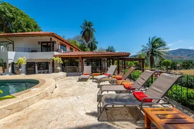 a group of lounge chairs sitting next to a pool at Luxury Five-Bedroom Oasis in Playa Flamingo with a Private Pool and Stylish Decor in Playa Flamingo