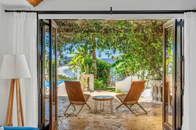 a living room with a patio with chairs and a table at Dreamy Spanish-Style Villa with Sweeping Ocean Views, Elegant Nautical Design & Giant Infinity Pool in Playa Flamingo