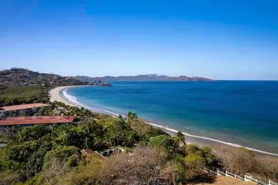 a view of a beach with trees and the ocean at Dreamy Spanish-Style Villa with Sweeping Ocean Views, Elegant Nautical Design & Giant Infinity Pool in Playa Flamingo