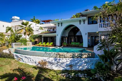a house with a swimming pool in front of a house at Dreamy Spanish-Style Villa with Sweeping Ocean Views, Elegant Nautical Design & Giant Infinity Pool in Playa Flamingo